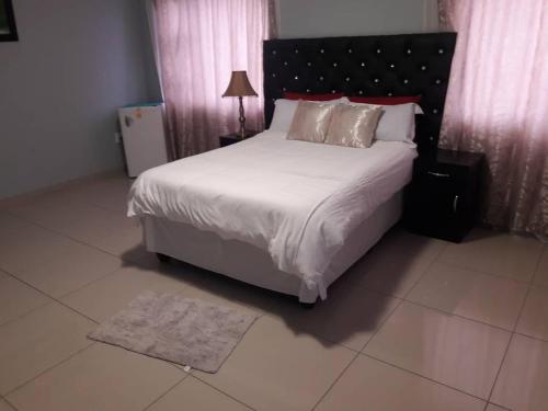 1 dormitorio con 1 cama grande con sábanas y almohadas blancas en Jessma Bed and Breakfast, en Walvis Bay