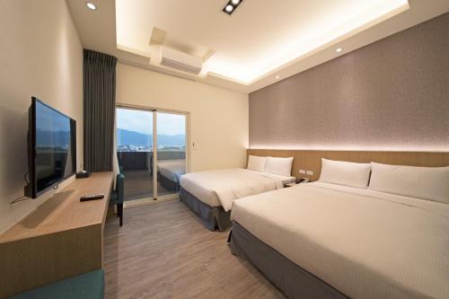 um quarto de hotel com duas camas e uma televisão de ecrã plano em Ruyi Inn em Taitung City