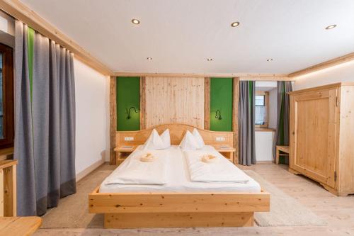 a bedroom with a wooden bed with white sheets at Das kleine Bio Hotel Tiefenbach in Schladming