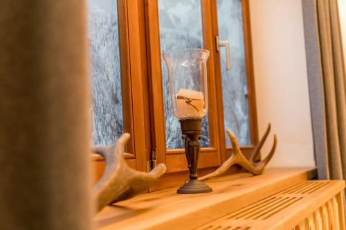 a glass candle on a window sill with deer antlers at Das kleine Bio Hotel Tiefenbach in Schladming