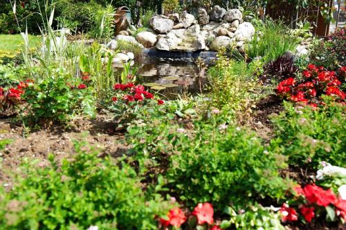 a garden with flowers and a pond and rocks at Hotel La Roseraie in Wemmel