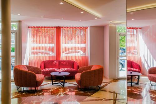 a lobby with red chairs and a table and windows at Mercure Paris Pont de Levallois Neuilly in Levallois-Perret