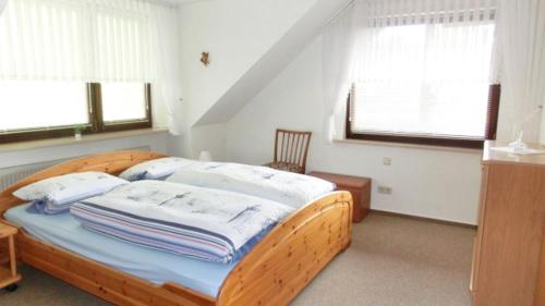 um quarto com uma cama de madeira e 2 janelas em Haus Müller em Heide