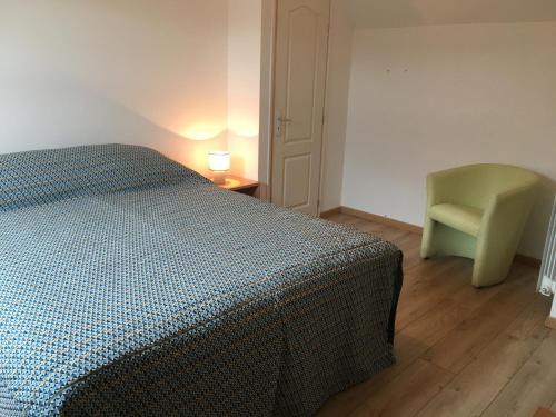 a bedroom with a bed and a green chair at Véro, Yves in Nay