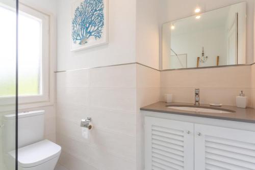 a bathroom with a toilet and a sink and a mirror at Villa Caprice in S'Algar