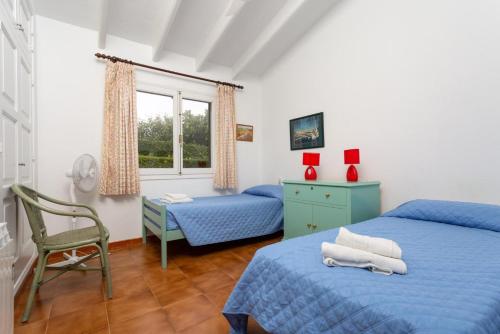 a bedroom with two beds and a desk and a window at Villa Caprice in S'Algar