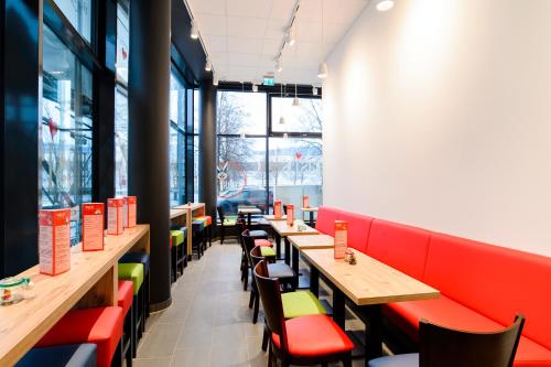 a restaurant with wooden tables and red chairs at Aparthotel my room - Messe Munich in Munich