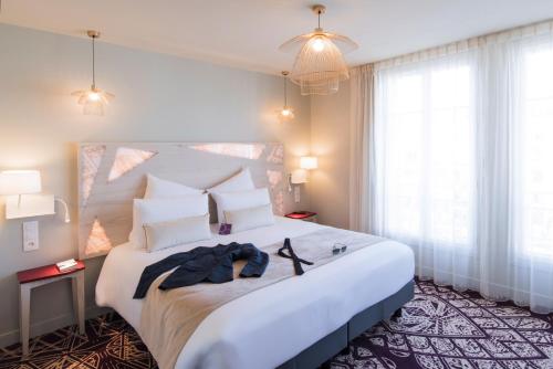 a hotel room with a large white bed with towels on it at Mercure Paris Pont de Levallois Neuilly in Levallois-Perret
