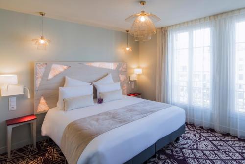 sypialnia z dużym białym łóżkiem i dużym oknem w obiekcie Mercure Paris Pont de Levallois Neuilly w mieście Levallois-Perret