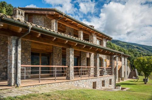 a large stone building with a deck on the side at Serrat del Vent - Adults only in Ribes de Freser