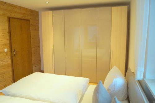 a bedroom with a white bed and a closet at Gästehaus Greiter - Sommer Bergbahnen inklusive in Oberstdorf