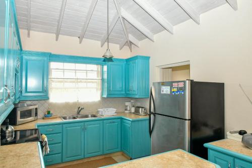 a kitchen with blue cabinets and a refrigerator at Best E Villas Providence in Christ Church