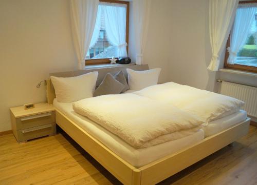 a bedroom with a bed with white sheets and a window at Gästehaus Greiter - Sommer Bergbahnen inklusive in Oberstdorf