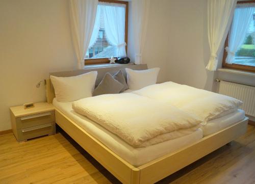 Schlafzimmer mit einem Bett mit weißer Bettwäsche und einem Fenster in der Unterkunft Gästehaus Greiter - Sommer Bergbahnen inklusive in Oberstdorf