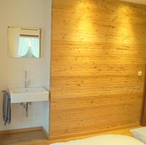 a bathroom with a sink and a wooden wall at Gästehaus Greiter - Sommer Bergbahnen inklusive in Oberstdorf