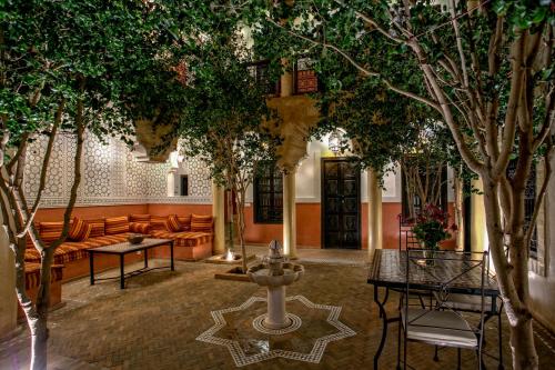 einen Innenhof mit Bäumen und einem Brunnen in einem Gebäude in der Unterkunft Riad Itrane in Marrakesch