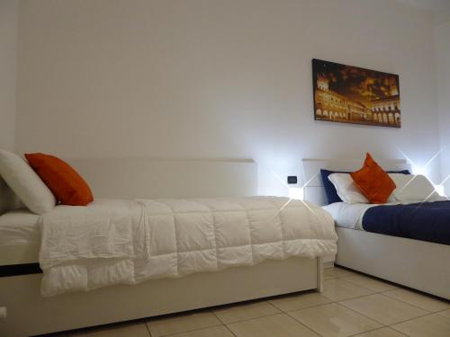 ボローニャにあるMontebello House Bolognaのベッドルーム1室(オレンジと青の枕が備わるベッド2台付)