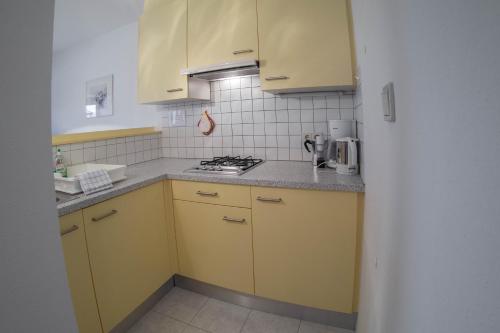 a kitchen with yellow cabinets and a stove at App. Tamanhof in San Giorgio