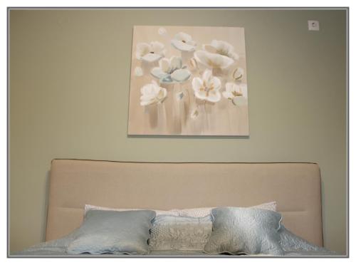 a picture of flowers on the wall above a bed at Apartment Libra in Novi Sad