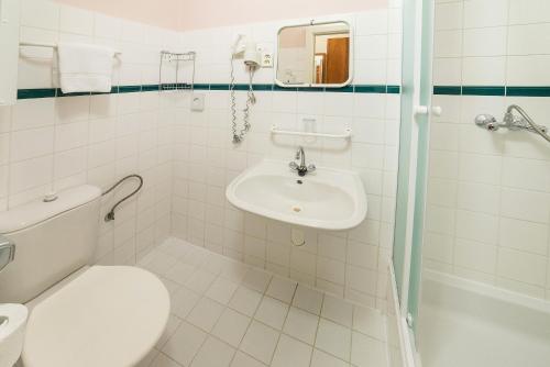 a white bathroom with a toilet and a sink at Dr. Adler Spa & Kurhotel in Františkovy Lázně