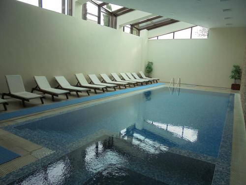 F307 Studio Aspen Golf Resort Bansko في بانسكو: A swimming pool with chairs and a swimming poolaster yasteryasteryasteryasteryastry