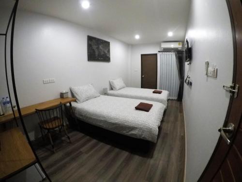 a small room with two beds and a desk at The Ghee House in Chiang Mai