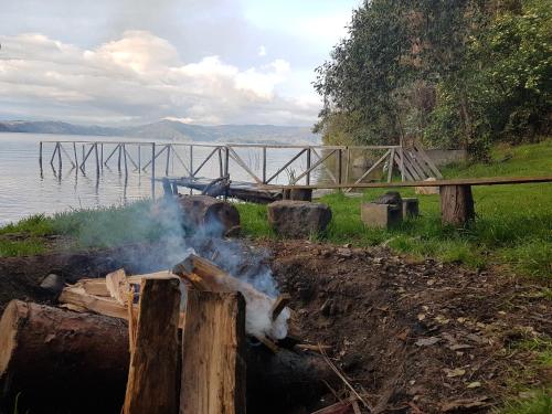 a fire pit with smoke coming out of it next to the water at Cabañas Yukatan Lago de Tota in Tota