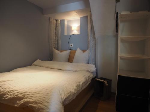 1 dormitorio pequeño con 1 cama con sábanas blancas en Tgantieni Sot - Apartment mit Herz, en Lenzerheide