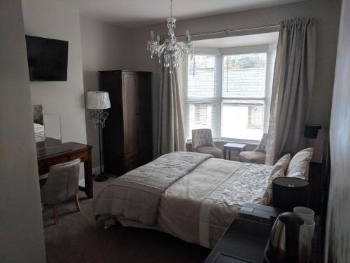 a bedroom with a bed and a desk and a window at Lion House Bed & Breakfast with Restaurant in Combe Martin