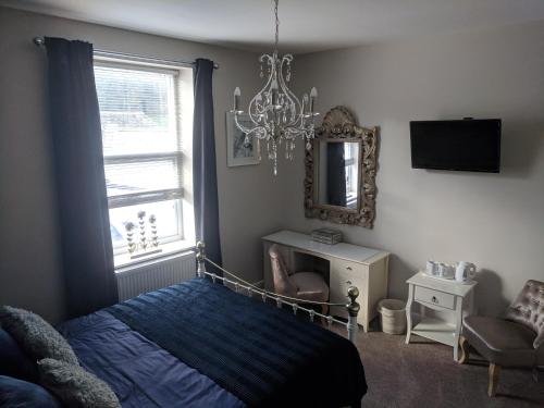 a bedroom with a bed and a mirror and a chandelier at Lion House Bed & Breakfast with Restaurant in Combe Martin