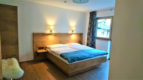 a bedroom with a bed with a wooden headboard and a window at Apart Troppmair in Aschau