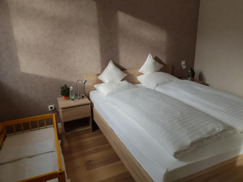 - une chambre dotée d'un grand lit avec des draps et des oreillers blancs dans l'établissement Meublés du 25 N2 F2 RDC, à Niederbronn-les-Bains