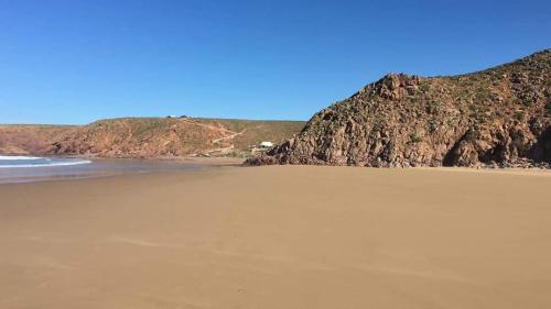 a sandy beach with a mountain in the background at Mirleft Point in Mirleft