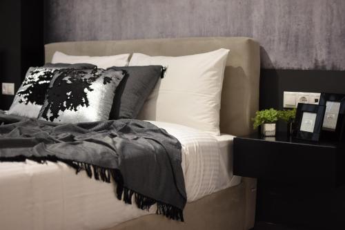 - un lit avec des draps et des oreillers en noir et blanc dans l'établissement Comely n Gusto luxury Apts.(Must), à Thessalonique