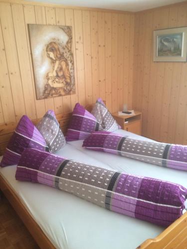a bed with purple and white pillows on it at Restaurant Felsenburg in Kandergrund