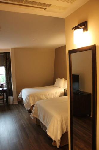 a hotel room with two beds and a mirror at Norwalk Inn & Conference Center in Norwalk