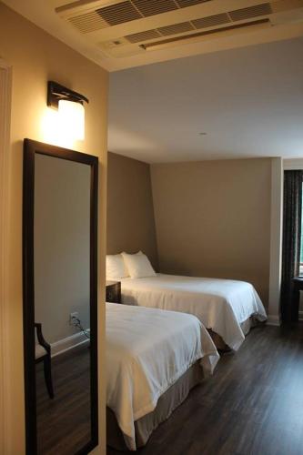 a hotel room with two beds and a mirror at Norwalk Inn & Conference Center in Norwalk