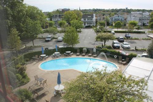 a pool with tables and chairs and a parking lot at Norwalk Inn & Conference Center in Norwalk