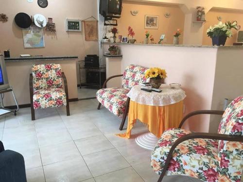 a living room with chairs and a table with flowers at Hospedagem Narcizo in São Lourenço