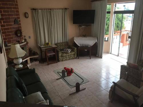 a living room with a couch and a tv at Hospedagem Narcizo in São Lourenço