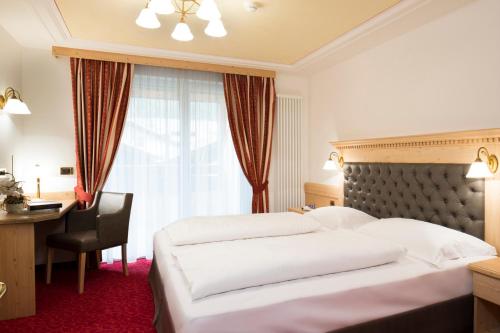 a hotel room with two beds and a desk and a window at Residence Isabell in Selva di Val Gardena
