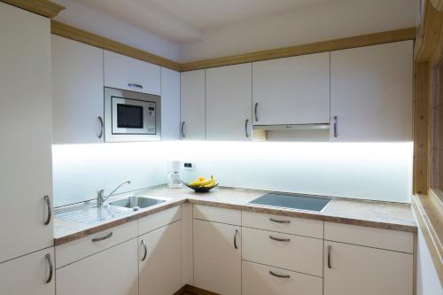 a white kitchen with white cabinets and a sink at Residence Isabell in Selva di Val Gardena