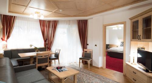 a living room with a couch and a room with a bed at Residence Isabell in Selva di Val Gardena