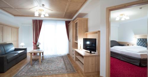 a hotel room with a bed and a couch and a television at Residence Isabell in Selva di Val Gardena
