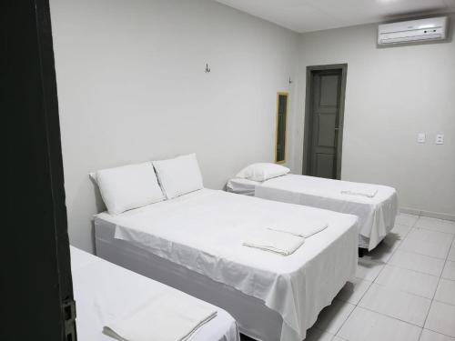 two beds in a room with white walls at Excelsior Hotel in Caxias das Aldeias Altas