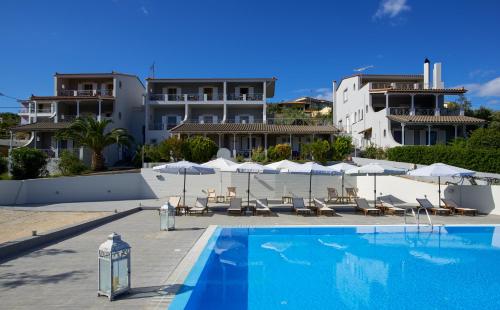a swimming pool with chairs and umbrellas next to a building at Irene Studios in Pefki