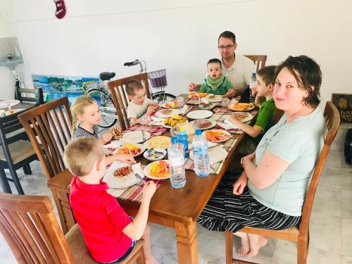 a family sitting at a table eating food at White Villa Airport Transit Hotel in Katunayake