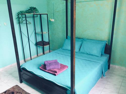 a four poster bed with blue sheets and pink towels at Deena Homestay (Utan Aji) in Kangar