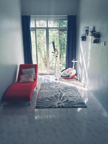 a living room with a red chair and a rug at Deena Homestay (Utan Aji) in Kangar