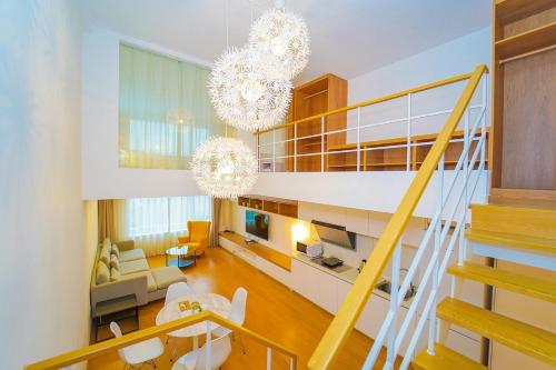 ein Wohnzimmer und eine Treppe mit Kronleuchtern in einem Haus in der Unterkunft Lujiazui More Residence in Shanghai